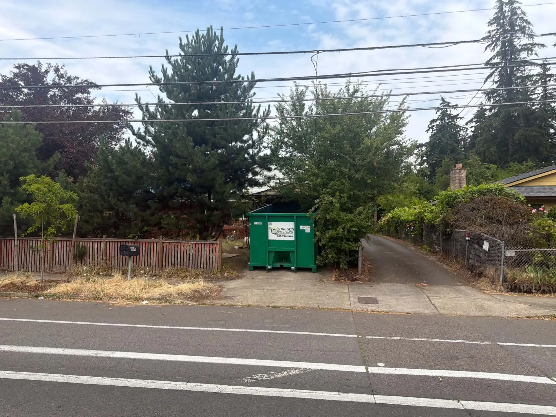 Oregon Recycling dumpster beside a driveway entrance with the approach visible.